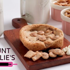 A bowl-shaped cashew cookie filled with cashews on a wooden board.