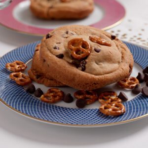 A chocolate chip cookie topped with pretzels on a blue plate.